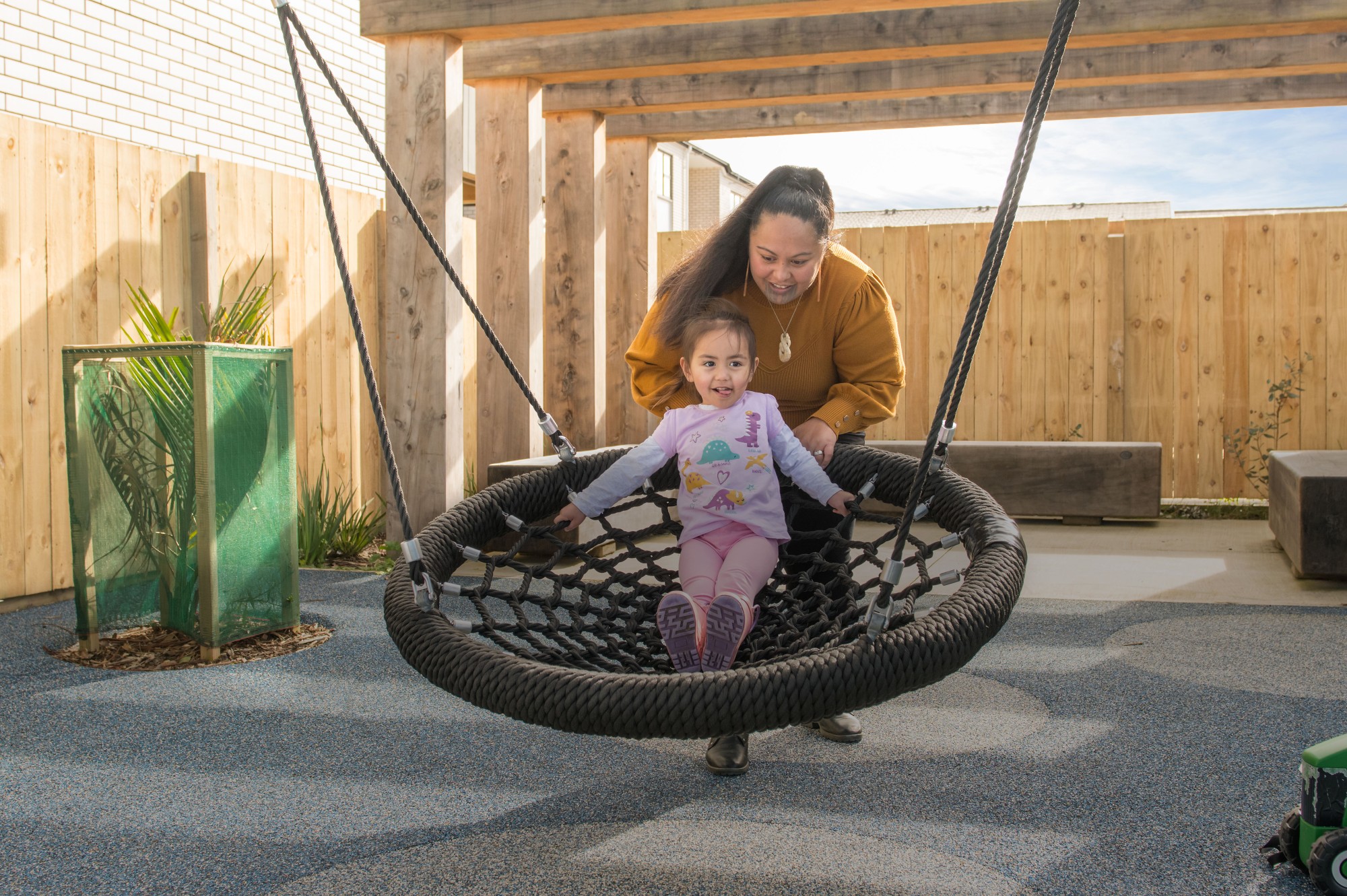 A mother and child enjoying a swing in a Puhinui Park playground